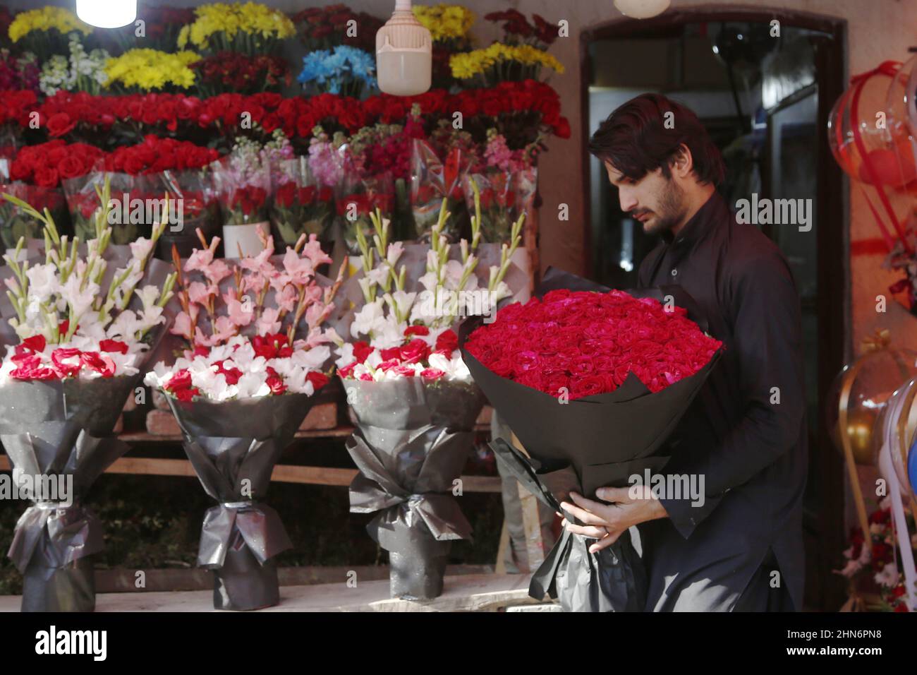 Islamabad, Pakistan. 14th Feb, 2022. A man carries roses at a flower