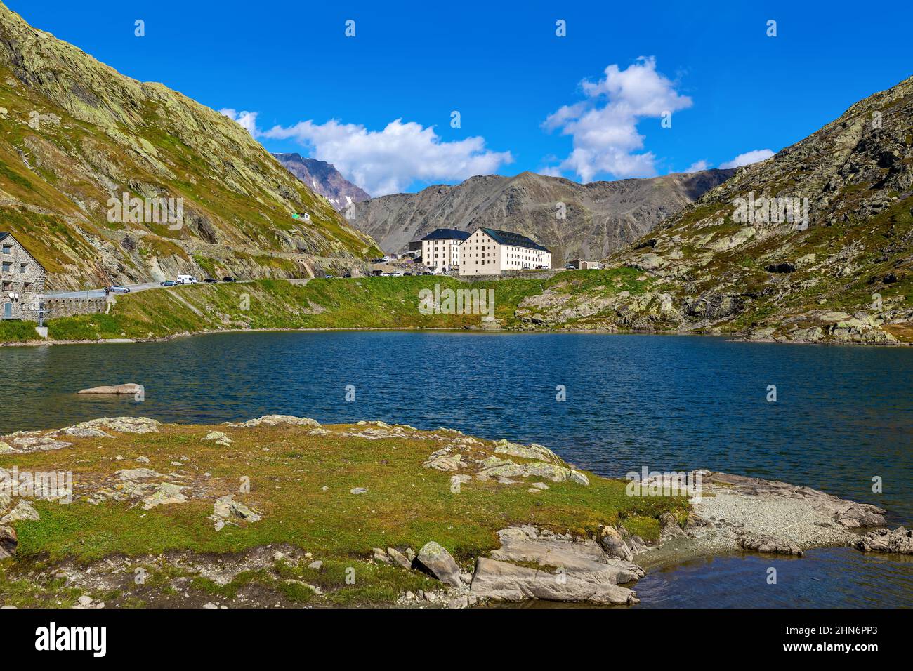 Small alpine lake among mountains under blue sky at the Great St Bernard mountain pass on the border between Italy and Switzerland. Stock Photo