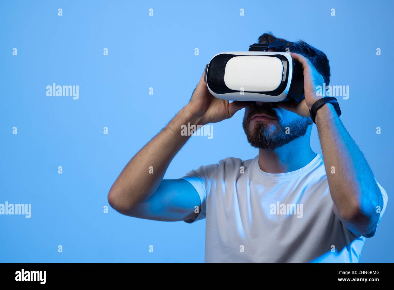 Close up portrait of young handsome attractive bearded man in vr glasses playing video games with virtual reality headset in a metaverse. Stock Photo