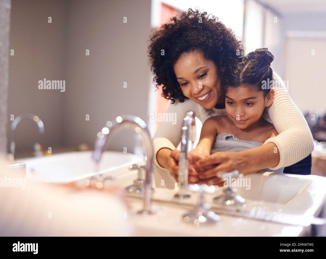 Lets get them good and clean. Cropped shot of a mother and daughter washing their hands at the bathroom sink. Stock Photo