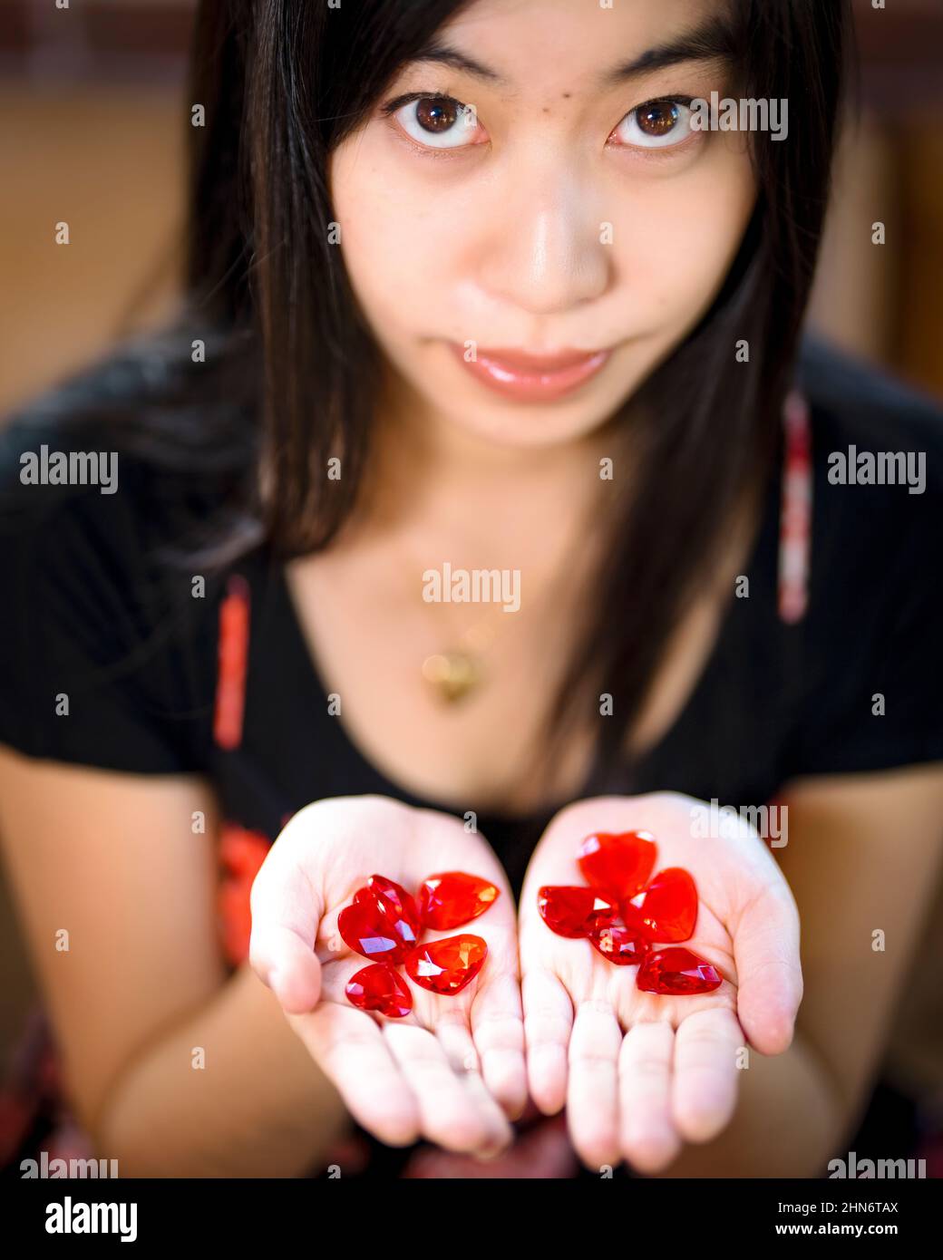 Young East Asian Woman Holding Red Heart Gems In Her Hands Stock Photo ...