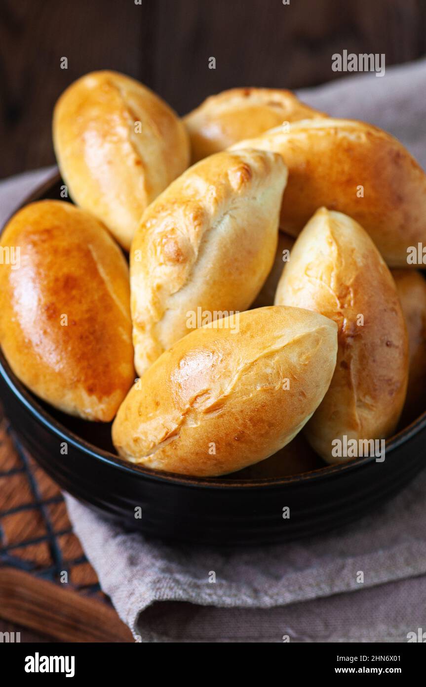 Potato stuffed hand pies in a black bowl on a wooden board. Overhead view. Stock Photo
