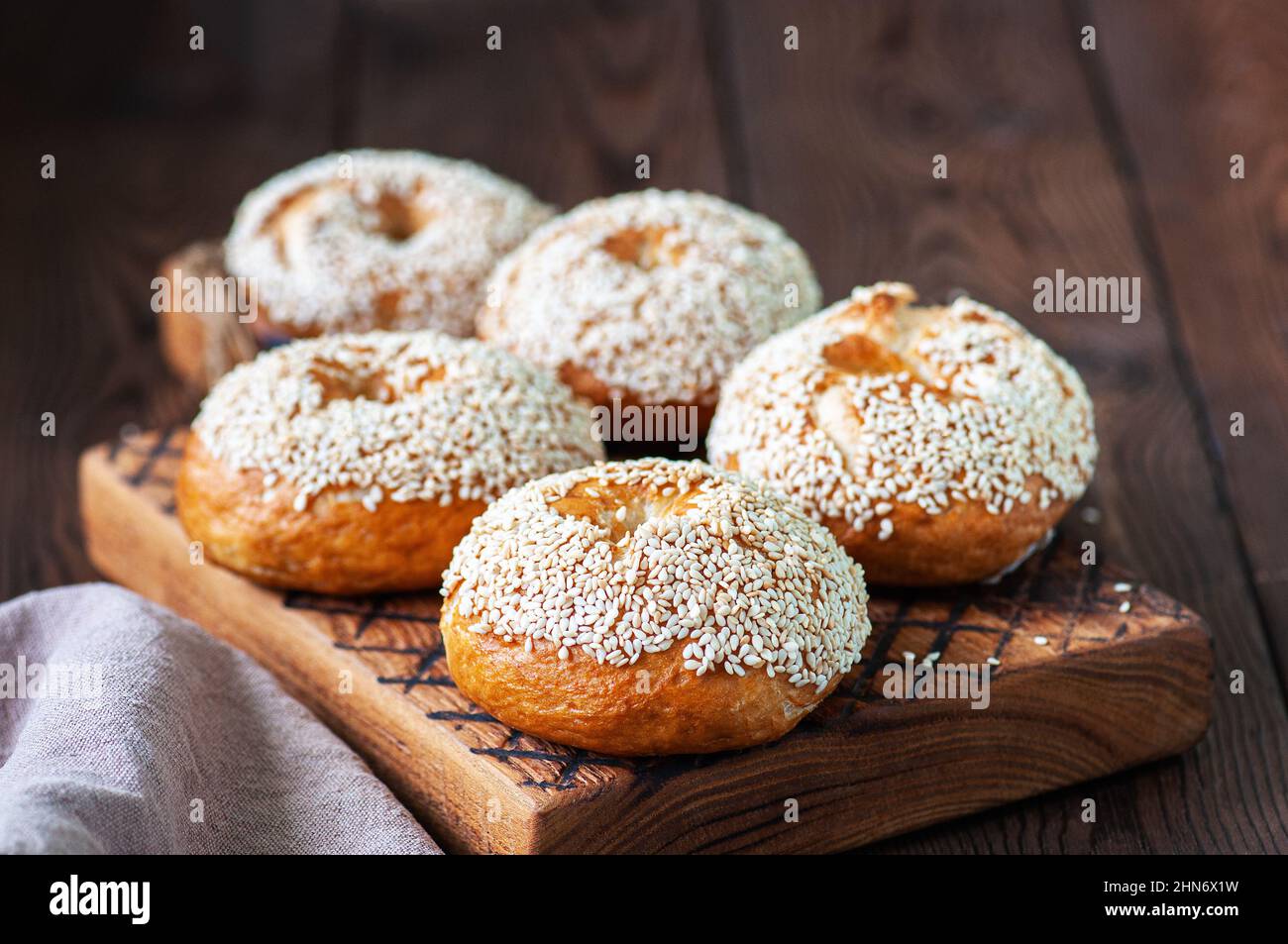 Freshly baked sesame seeded bagels on a wooden background. Stock Photo