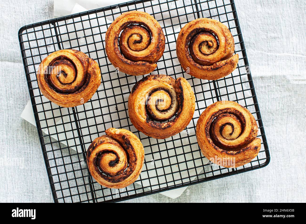 Top view of aromatic homemade yeasty buns with cinnamon on a cooling rack. White background. Stock Photo