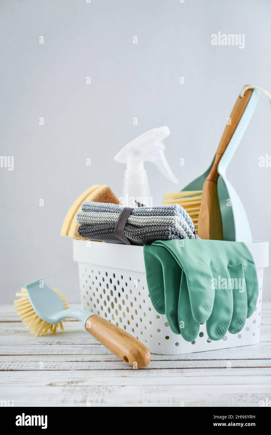 Set of cleaning supplies in blue color in plastic basket on blue