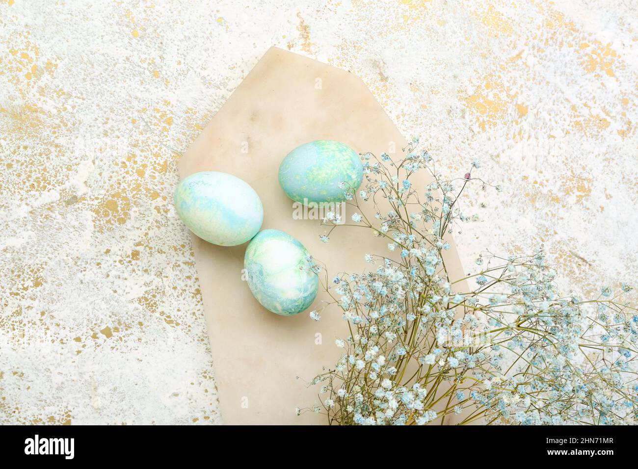 Board with beautiful Easter eggs and gypsophila flowers on light ...
