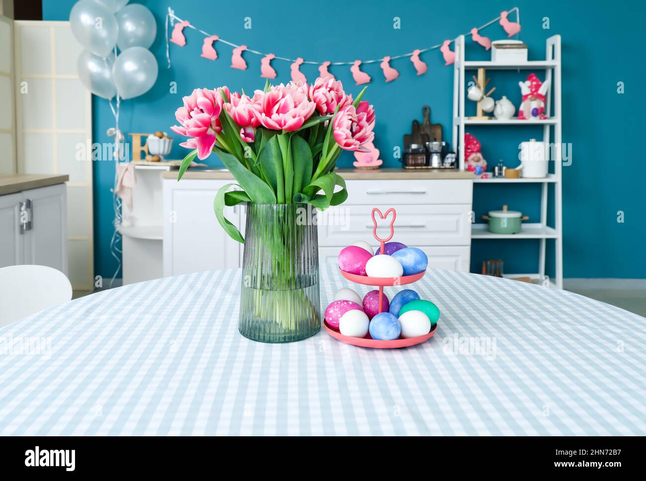 Stand with Easter eggs and vase with tulips on dining table Stock Photo ...