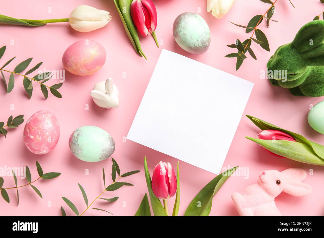 Composition with blank card, flowers and Easter eggs on pink background ...