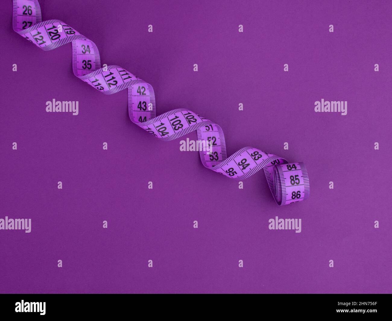 Purple tape measure on the violet background Stock Photo - Alamy
