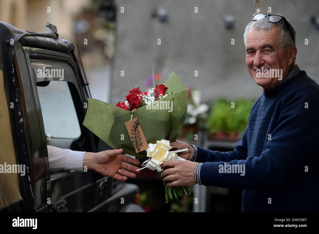 Gozo, Malta. 14th Feb, 2022. A flower shop owner hands a bouquet of