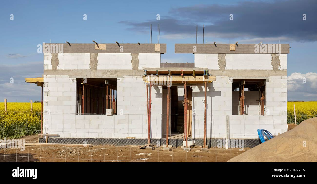Rural house under construction with rapeseed field in background. Stock Photo