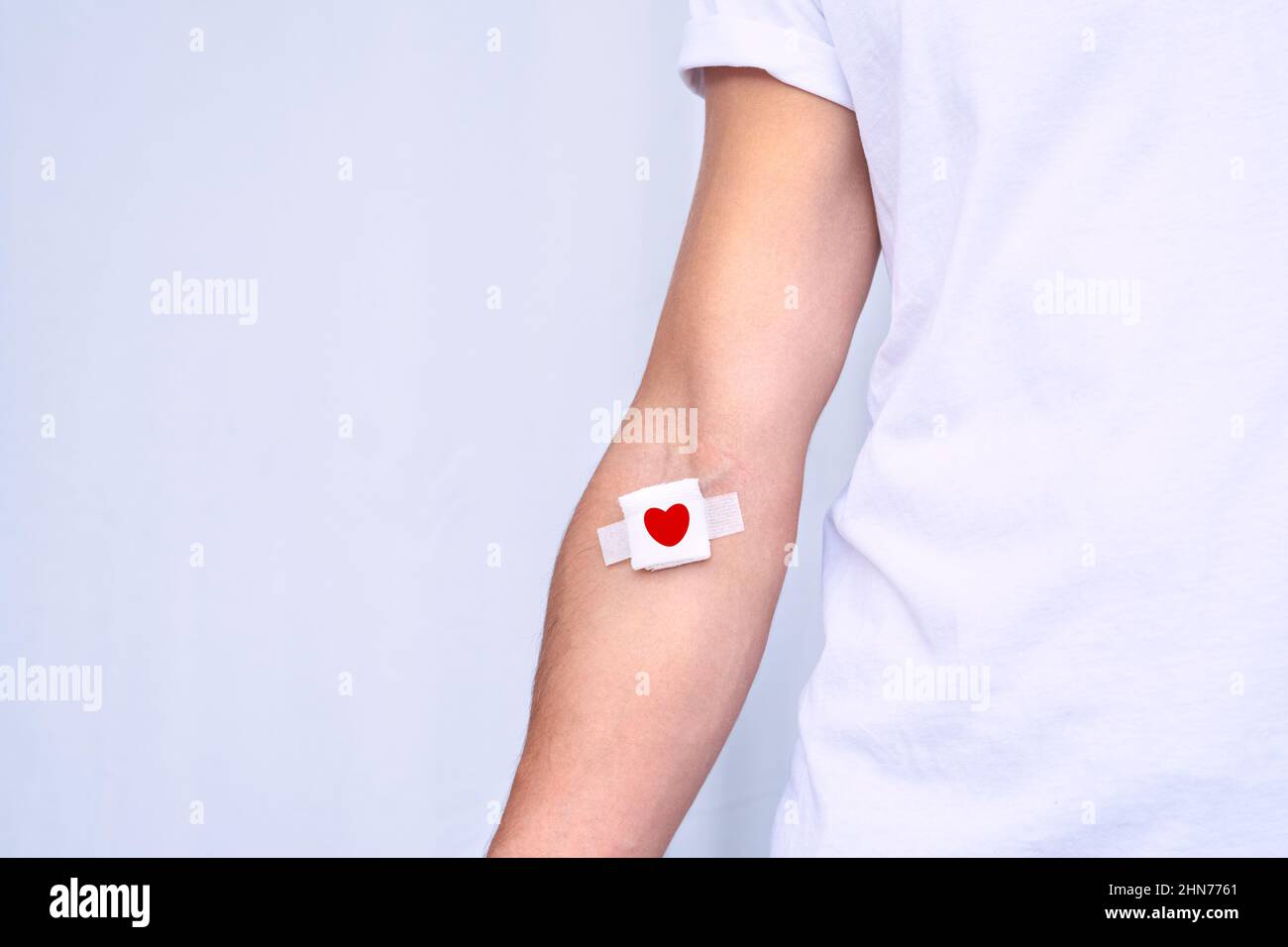Blood donation concept with copy space. Blood donor with bandage after giving blood on a white