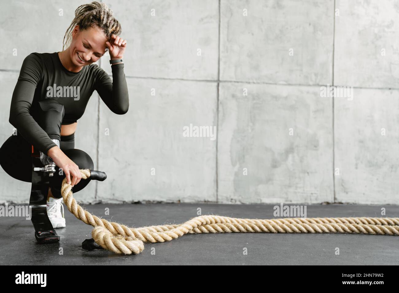 Young woman with prosthesis using battle ropes while working out ...