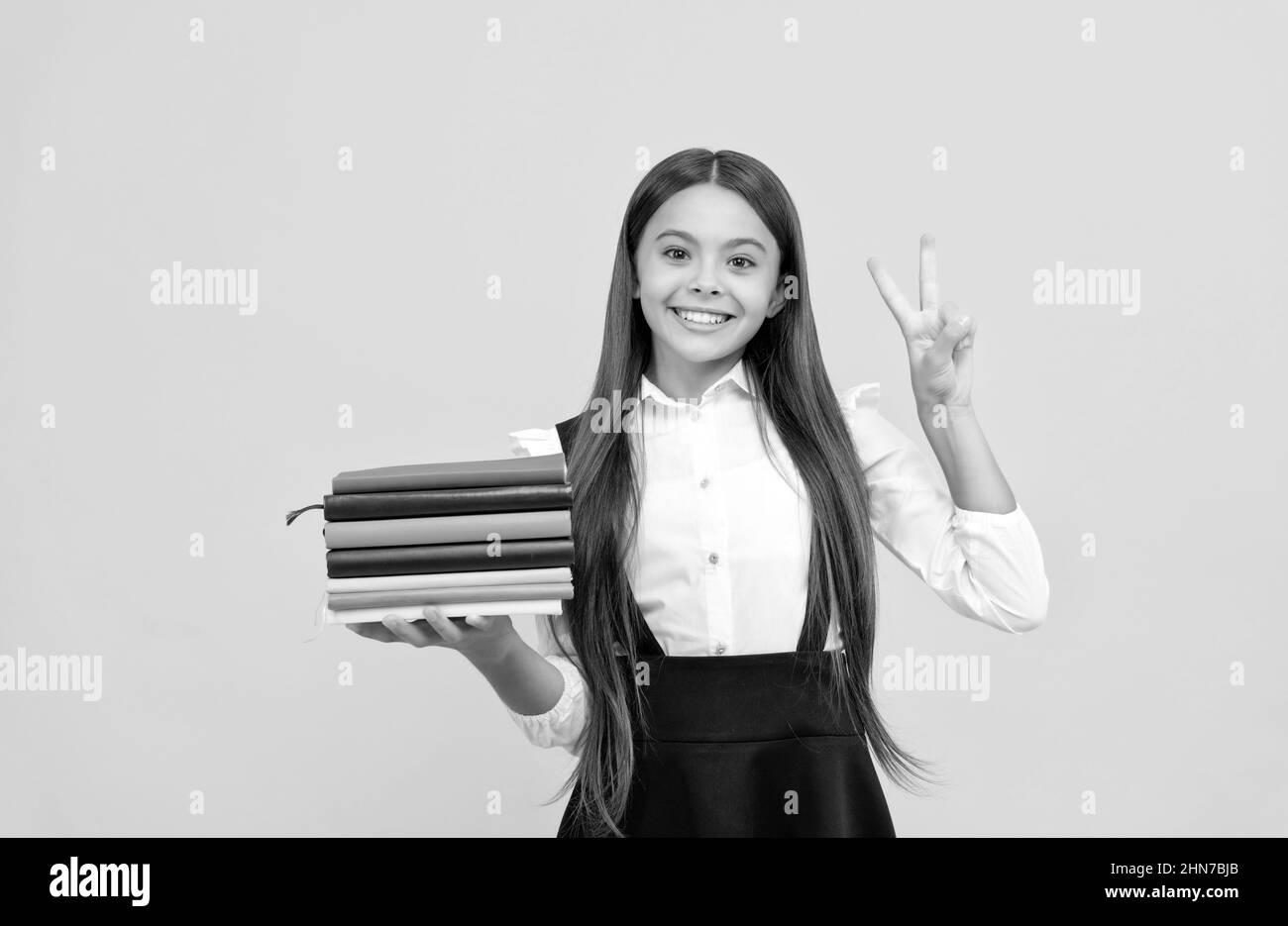 happy teen girl in school uniform hold book stack show peace gesture ...