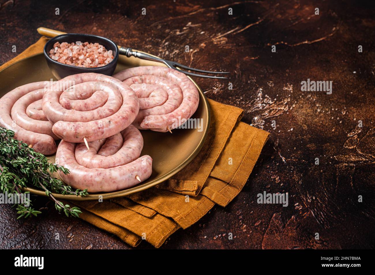 Raw spiral pork sausages, uncooked Wurst. Dark background. Top view. Copy space Stock Photo