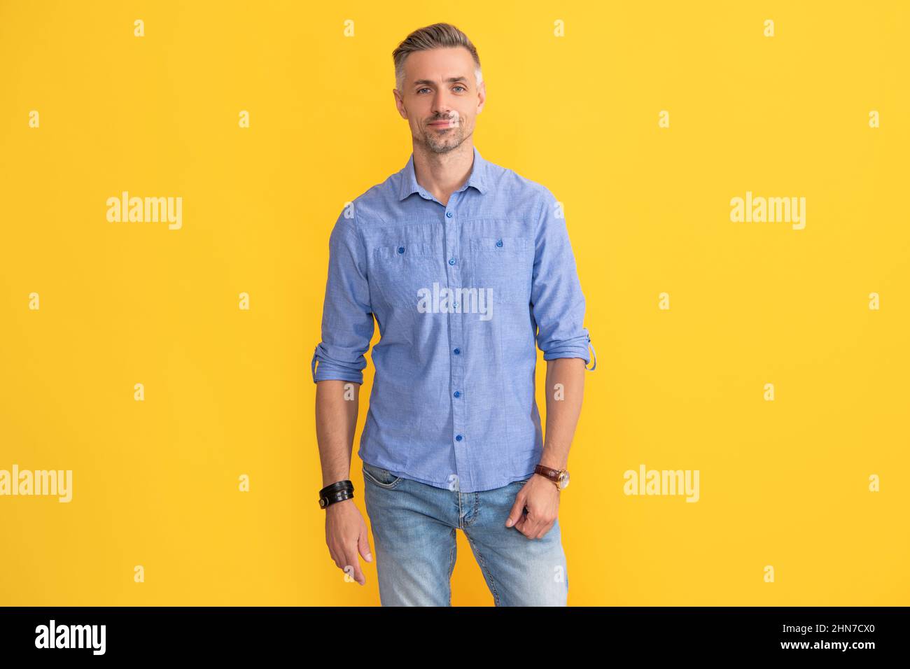 smiling adult man with hand watch on yellow background, fashion accessory Stock Photo