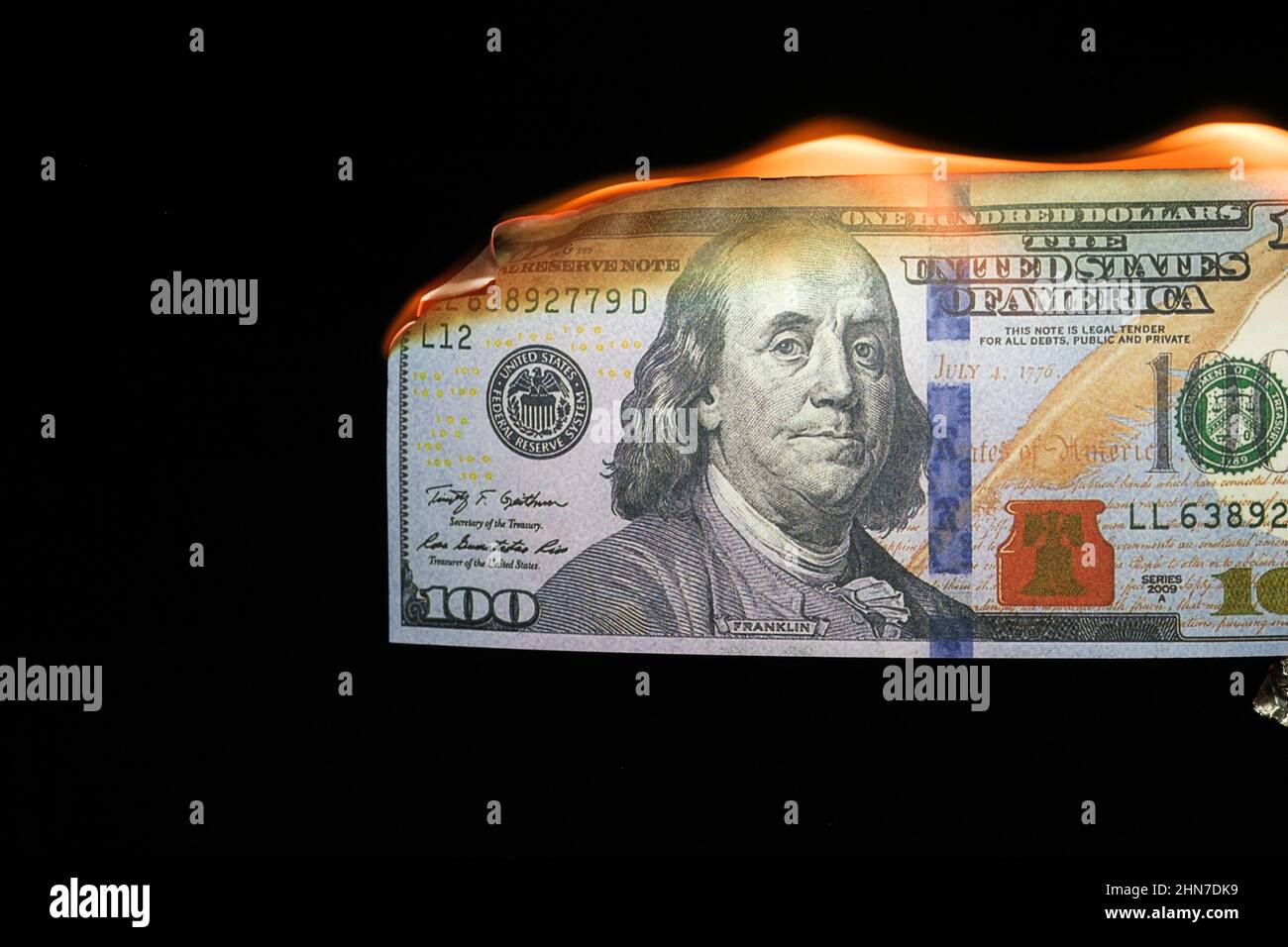 Close up shot of a 100 dollar banknote burning on a black background. Stock Photo