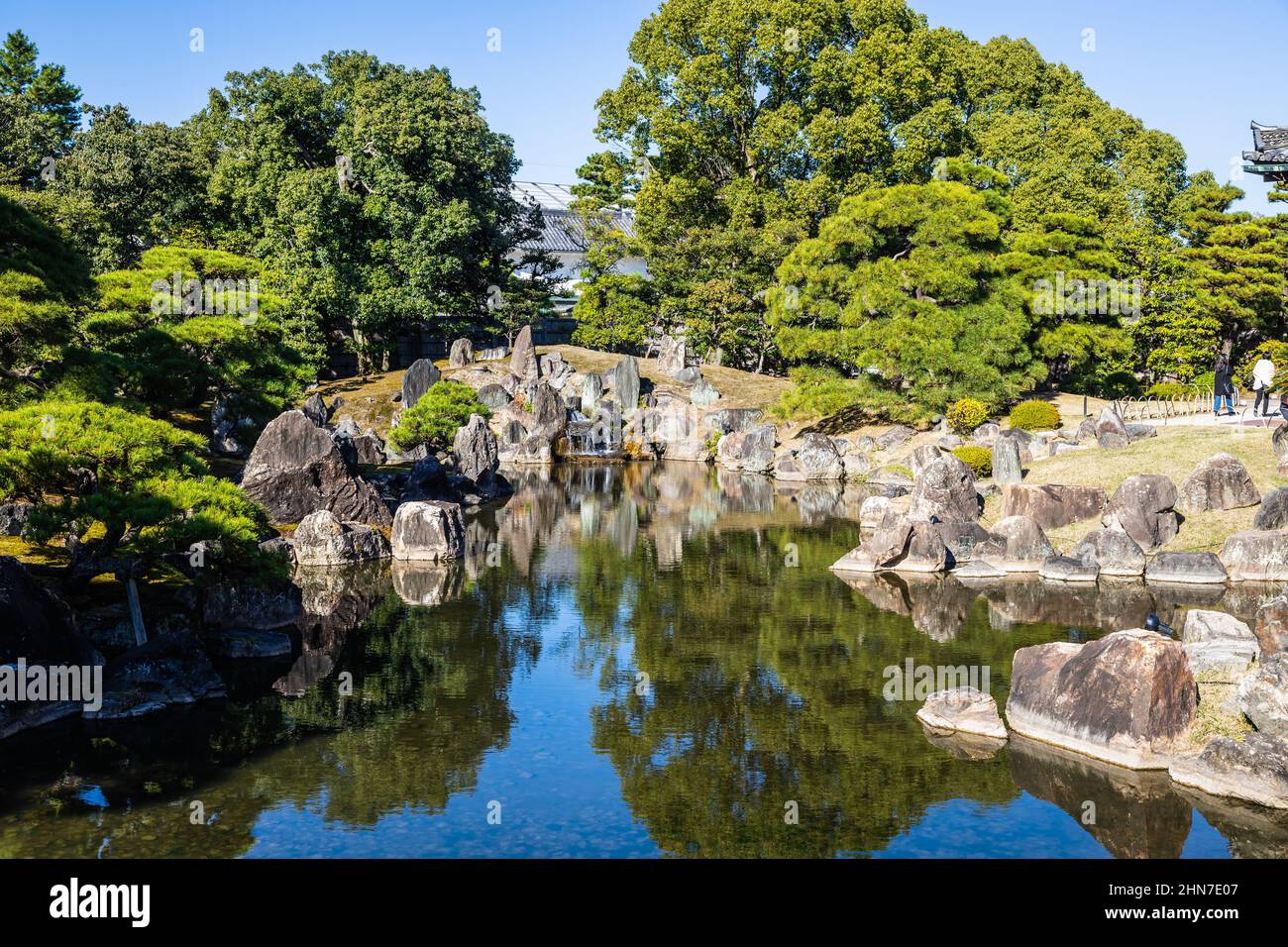 Japanese Garden with a shallow pond and rocks surrounding the edge in daylight. Stock Photo