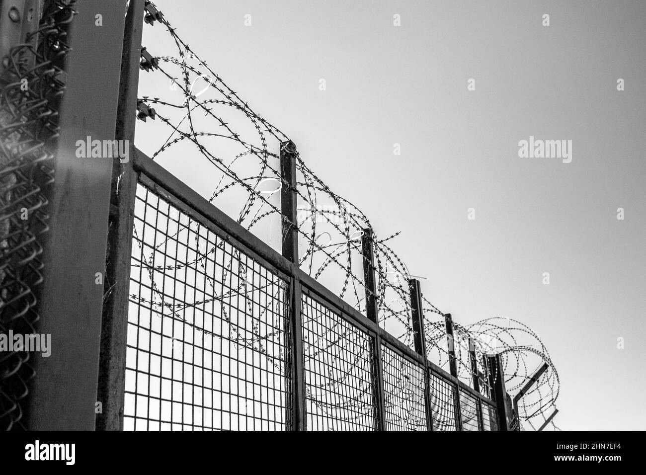 Military installation barbed wire fence. Monochrome image. Cold War. Conflict. secure area, keep out. Restricted area. Stock Photo