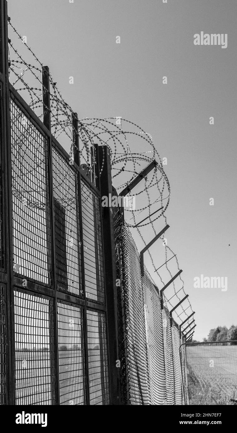 Razor wire security gate on a UK military base. USAF base at RAF Fairford. Monochrome image. Stock Photo