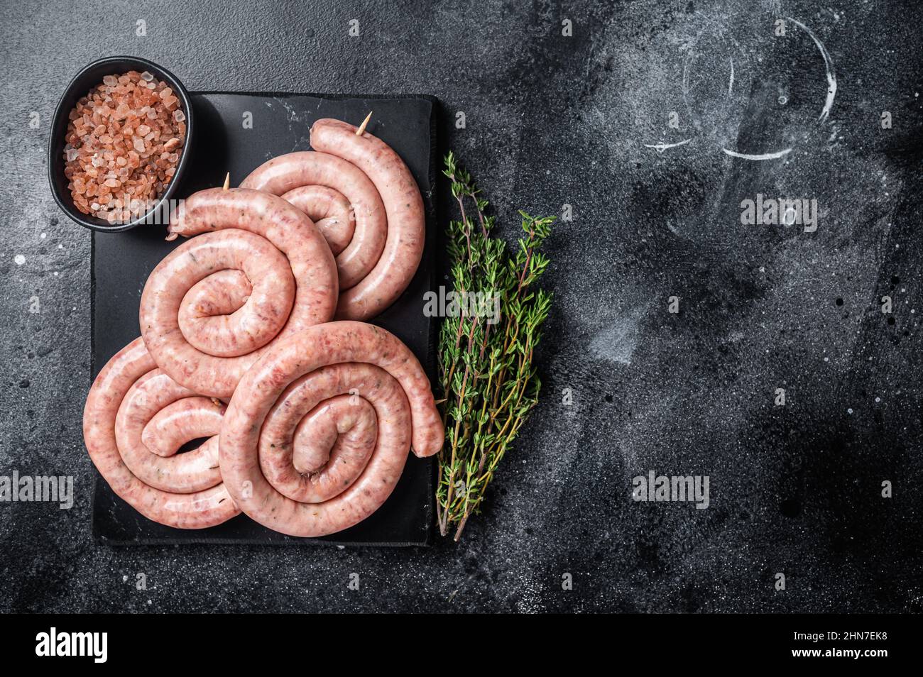 Traditional Raw spiral sausages on a marble board with thyme. Black background. Top view. Copy space Stock Photo