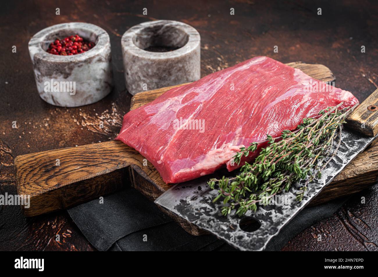 Alternative raw flap flank beef meat steak on butcher board. Dark background. Top view Stock