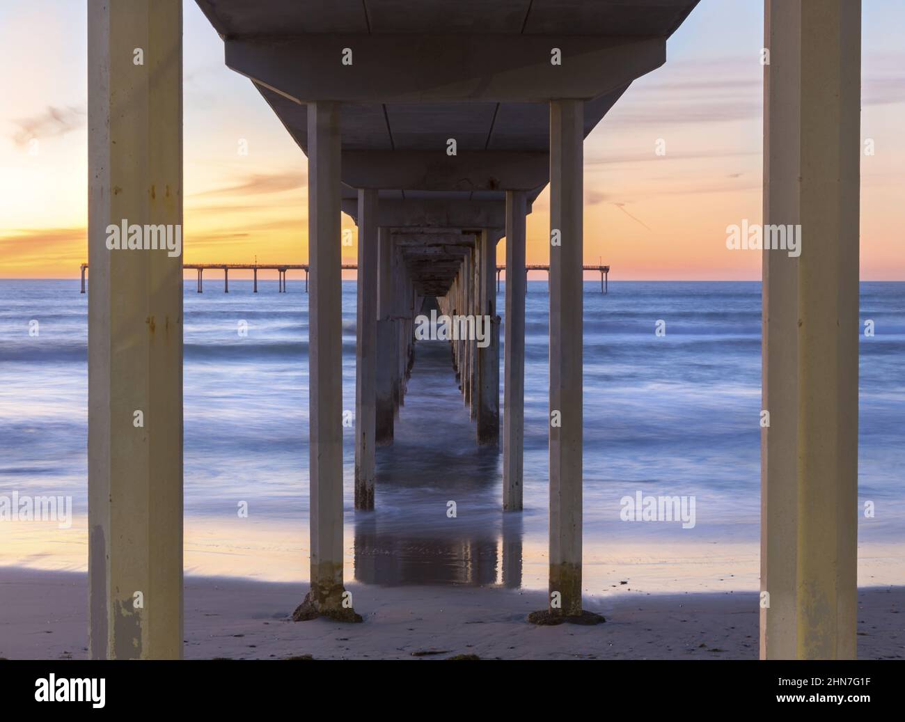 View Under Ocean Beach Pier Wooden Structure with Distant Orange Color Sunset Sky on Horizon in San Diego, Southern California Stock Photo