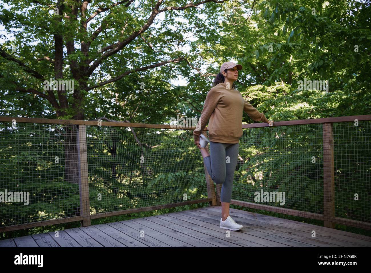 Mid adult woman doing exercise outdoors on terrace of tree house, weekend away and digital detox. Stock Photo
