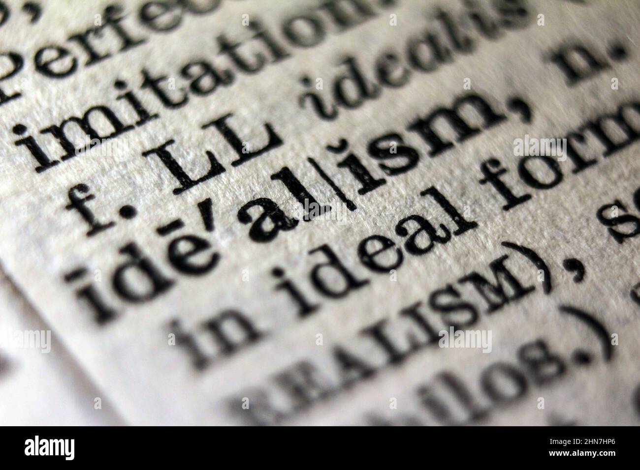Word 'idealism' printed on dictionary page, macro close-up Stock Photo