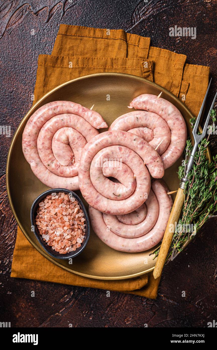 Raw spiral pork sausages, uncooked Wurst. Dark background. Top view Stock Photo