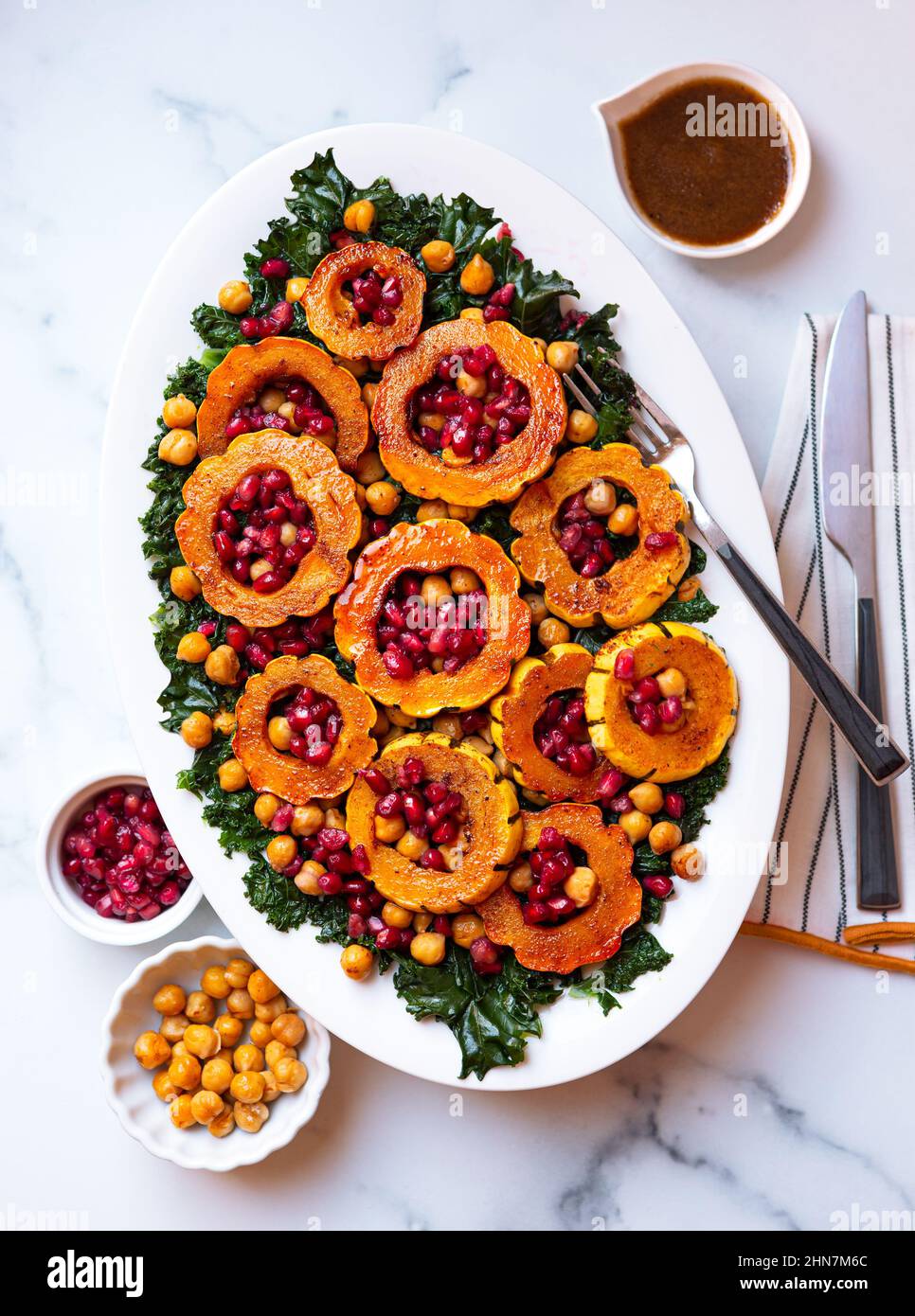 Overhead view of a plant-based salad made from delicata squash, wilted kale, chickpeas and pomegrante seed Stock Photo