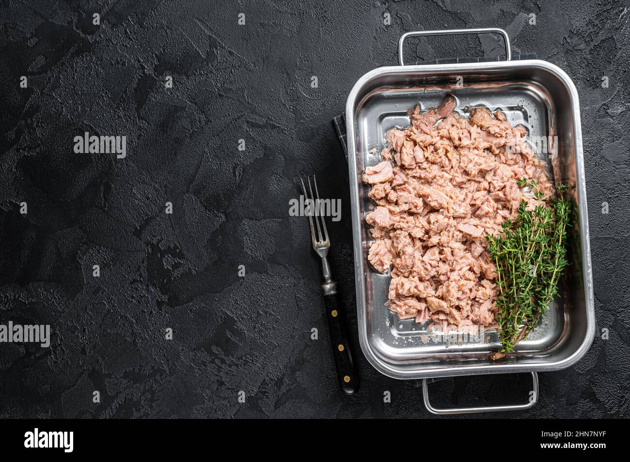 Tuna canned fish with olive oil in a tray . Black background. top view