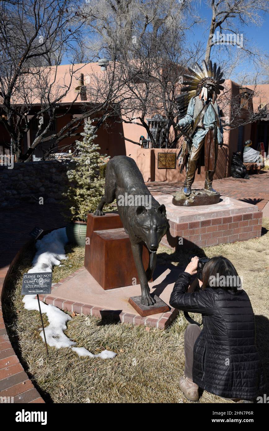 A tourist photographs a bronze sculpture of a wolf for sale at an art gallery in Santa Fe, New Mexico. Stock Photo