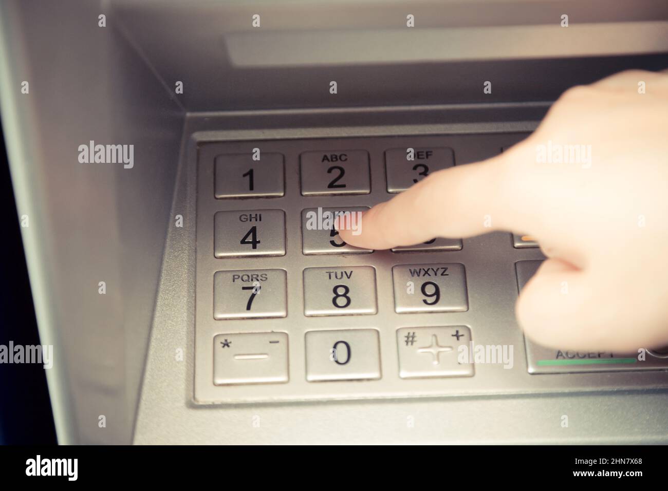 Close up of hand entering pin code at ATM machine to withdraw her money Stock Photo