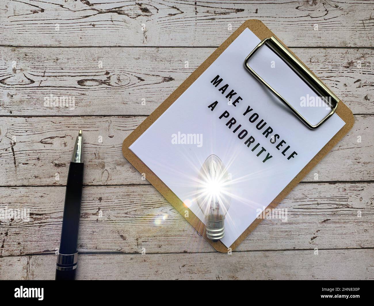 Top view of text on notepad - Make yourself a priority. With light bulb ...