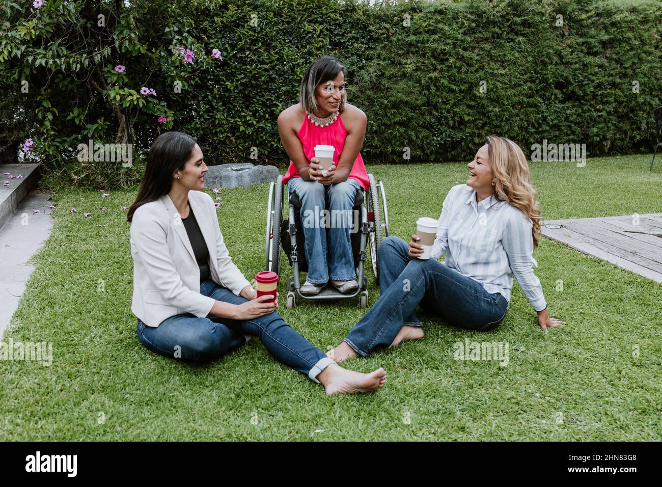latin business woman transgender on wheels chair and friends sitting on grass and meditating at terrace office in Mexico Latin America Stock Photo