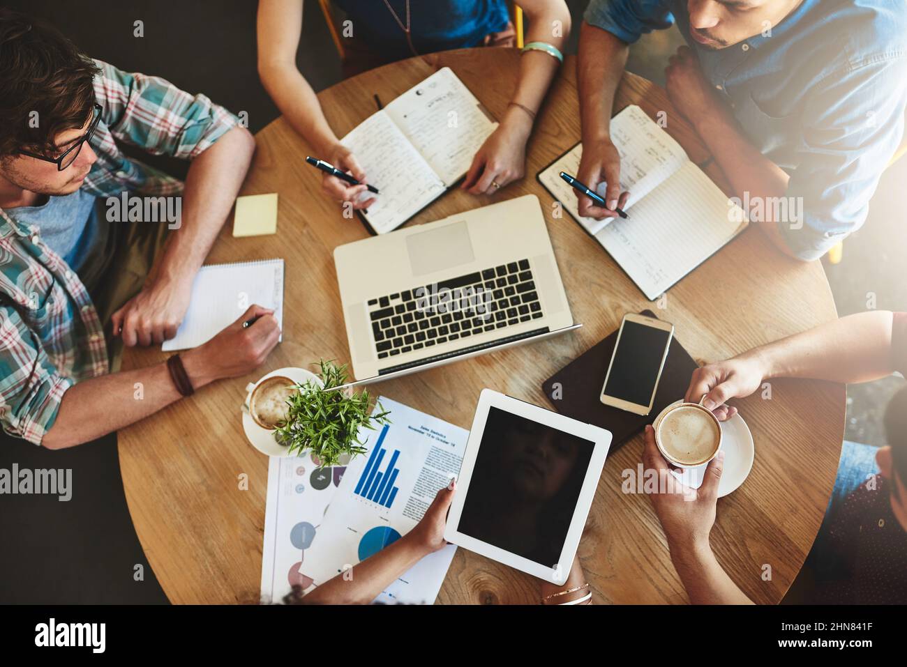 Sharing information thatll help them pass their exams. High angle shot of a group of students studying in a coffee shop. Stock Photo