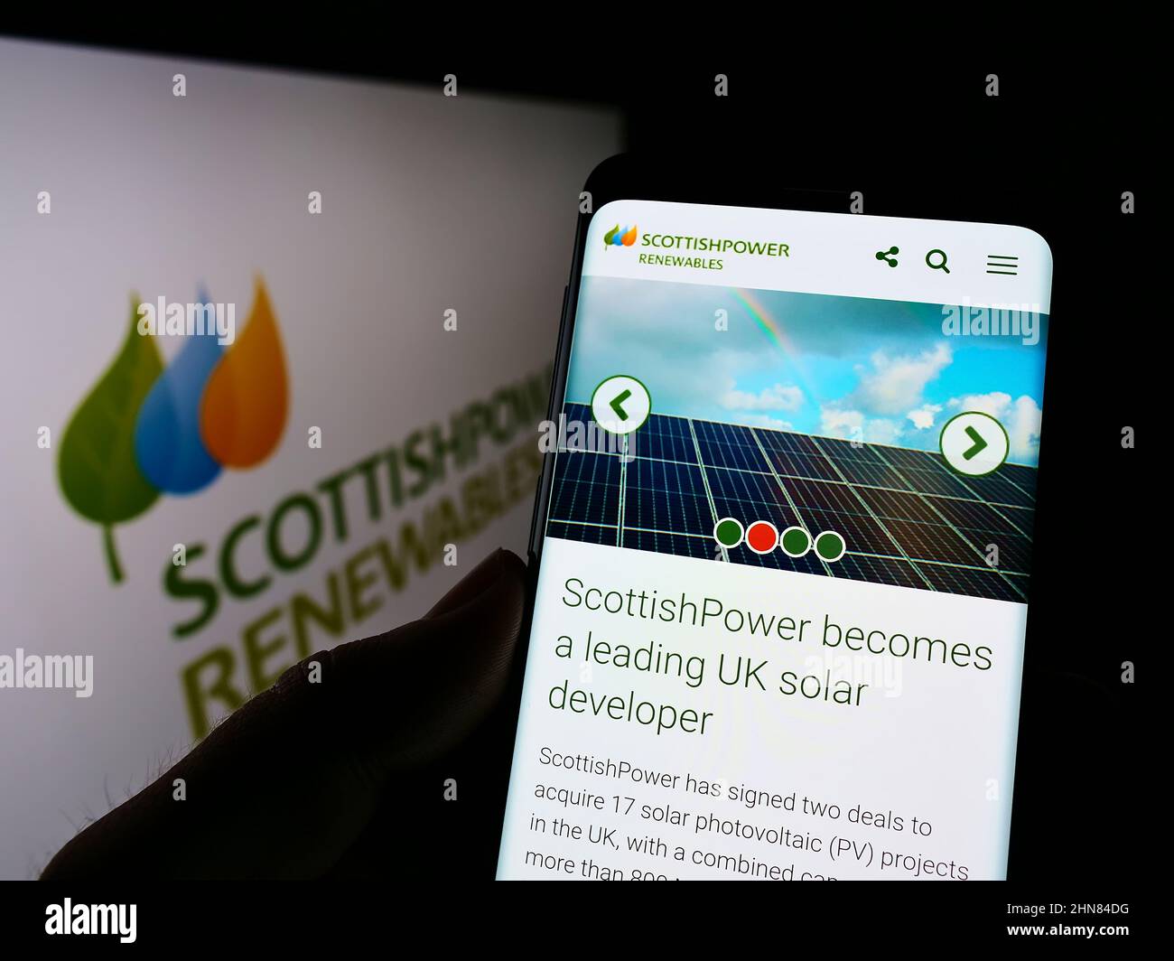 Person holding smartphone with website of company ScottishPower Renewables (UK) Limited on screen with logo. Focus on center of phone display. Stock Photo