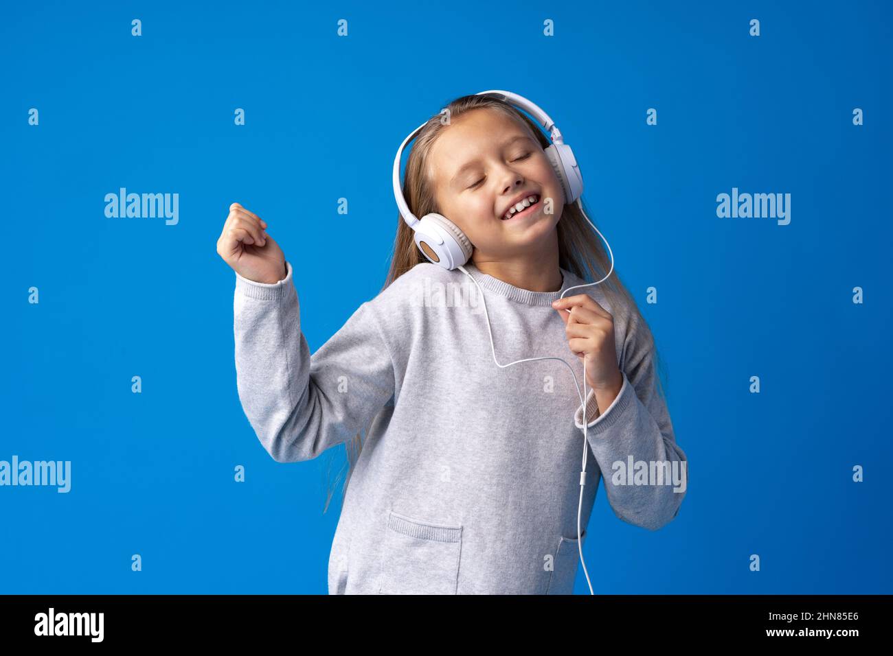 Little girl child wear headphones listen to music over blue background