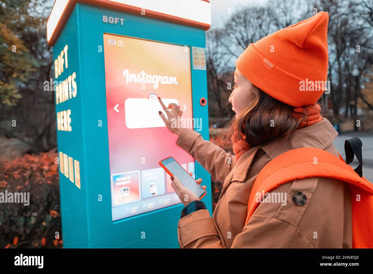 19 October 2021, Moscow, Russia: woman uses a self-service kiosk to print photos from her smartphone on a city street Stock Photo