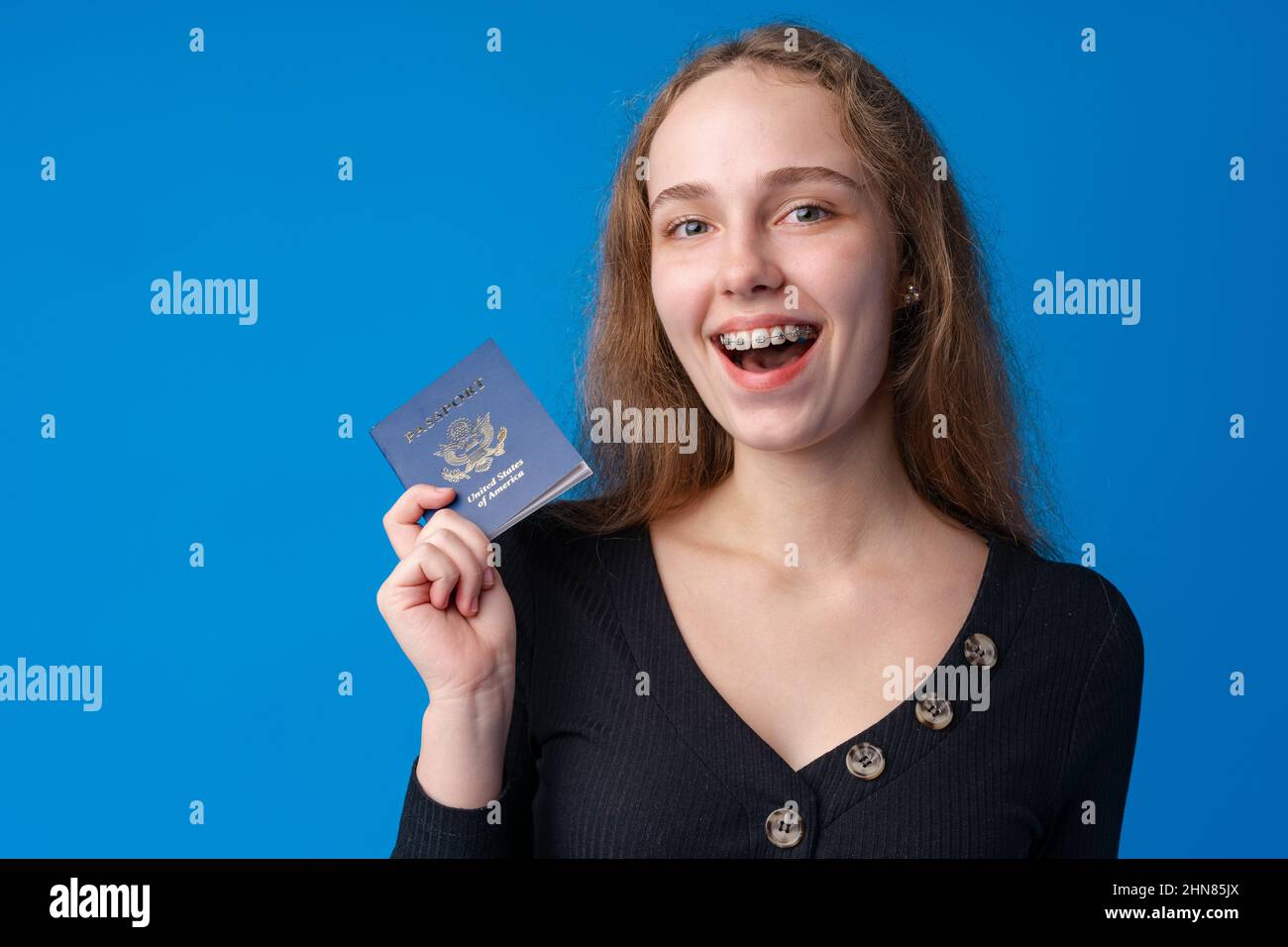 Teen girl holds a passport against blue background Stock Photo - Alamy