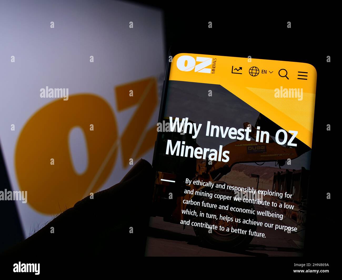 Person holding cellphone with website of Australian mining company OZ Minerals Limited on screen with logo. Focus on center of phone display. Stock Photo