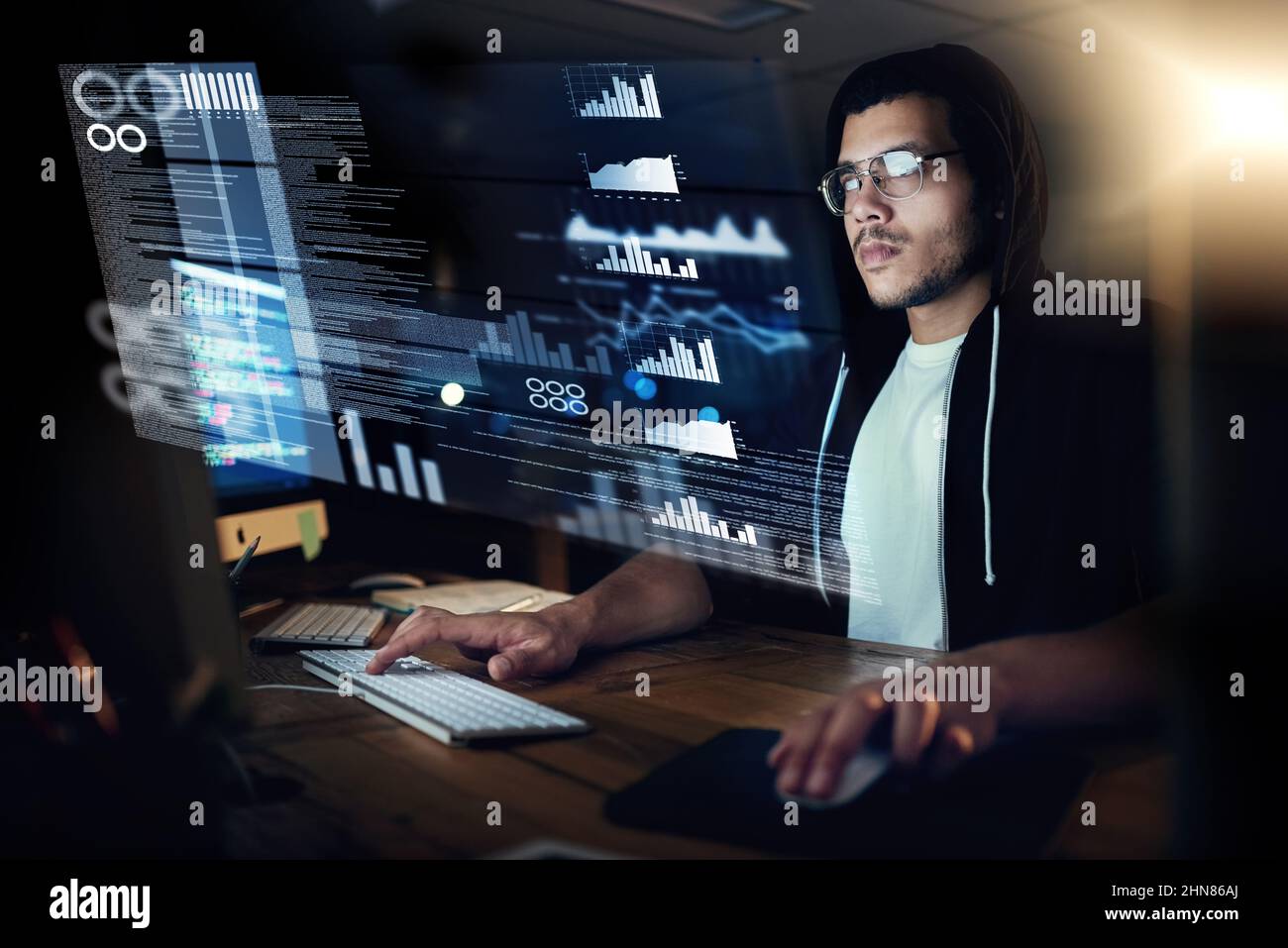 Pulling the strings through programming. Shot of a young hacker cracking a computer code in the dark. Stock Photo