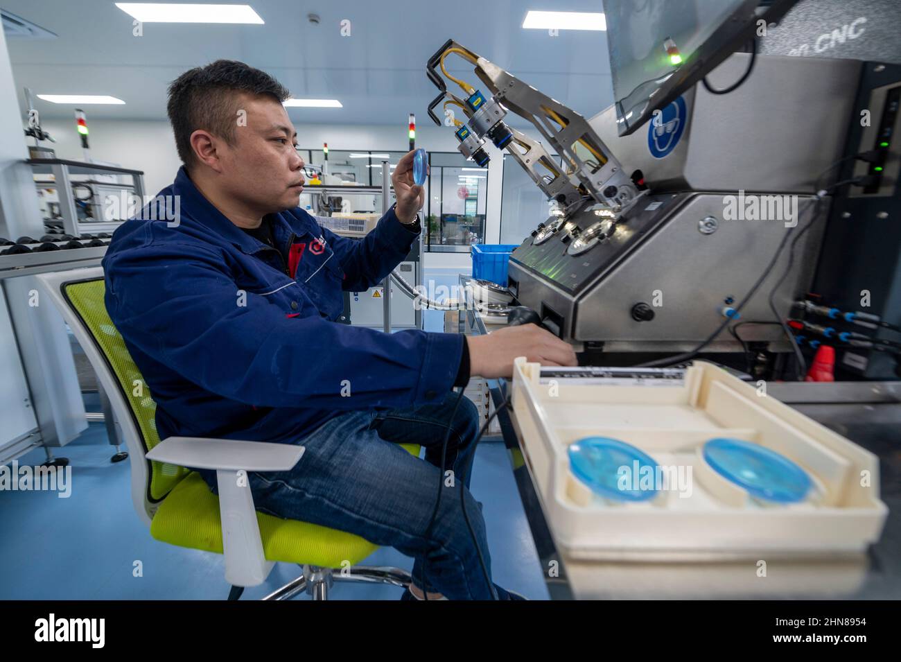 DANYANG, CHINA - FEBRUARY 15, 2022 - A technician makes optical lenses at a dust-free workshop in Danyang, Jiangsu Province, China, February 15, 2022. Stock Photo