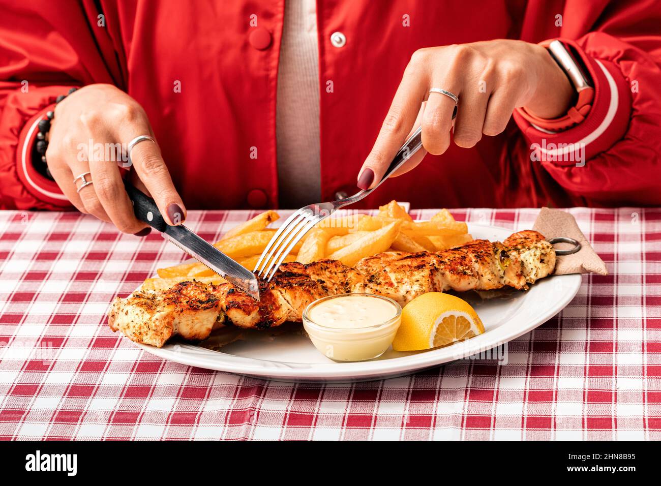 A girl using a knife and fork to eat traditional Greek grilled meat