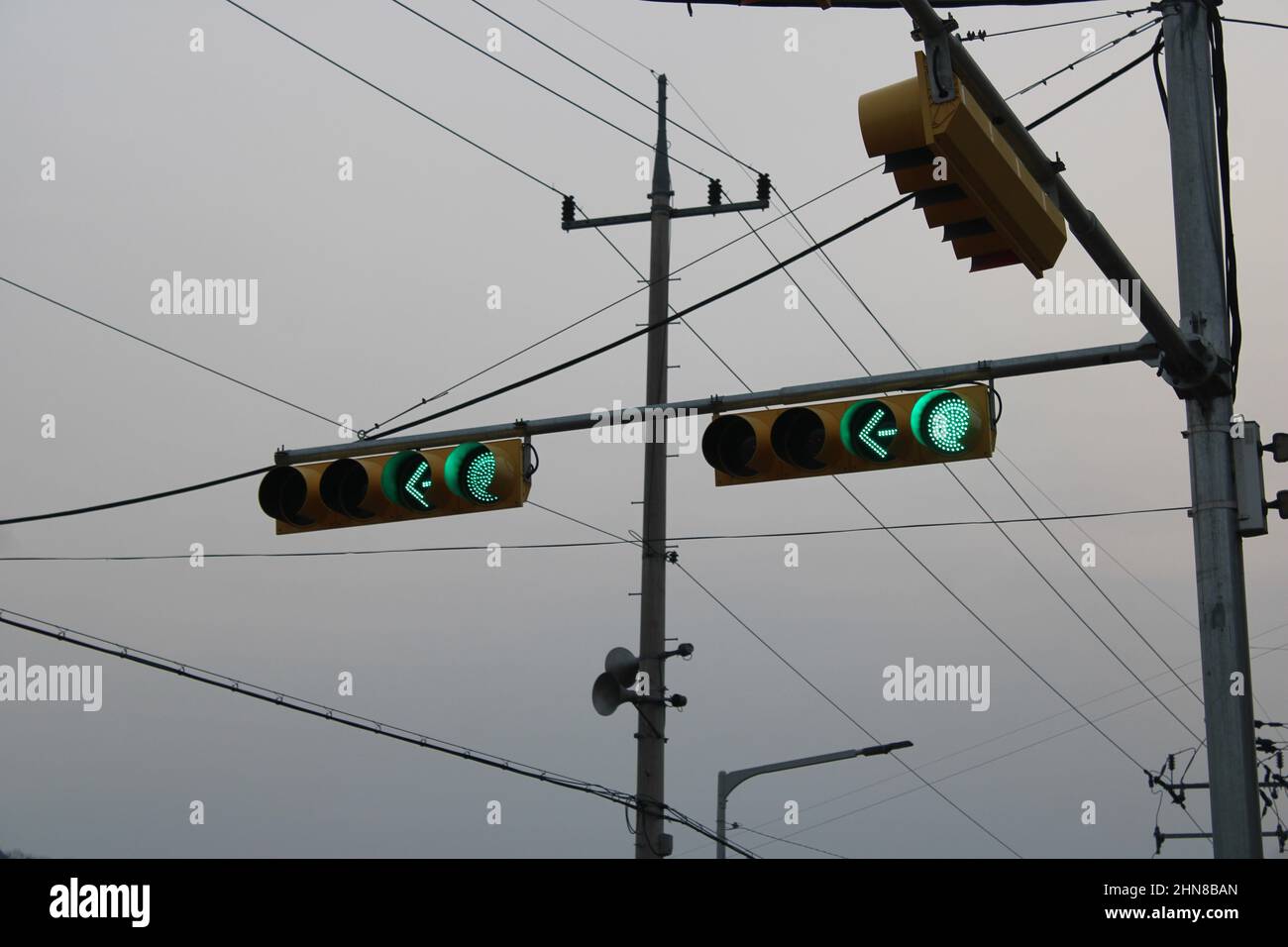 Green lights and arrows over traffic intersection, during stormy weather Stock Photo