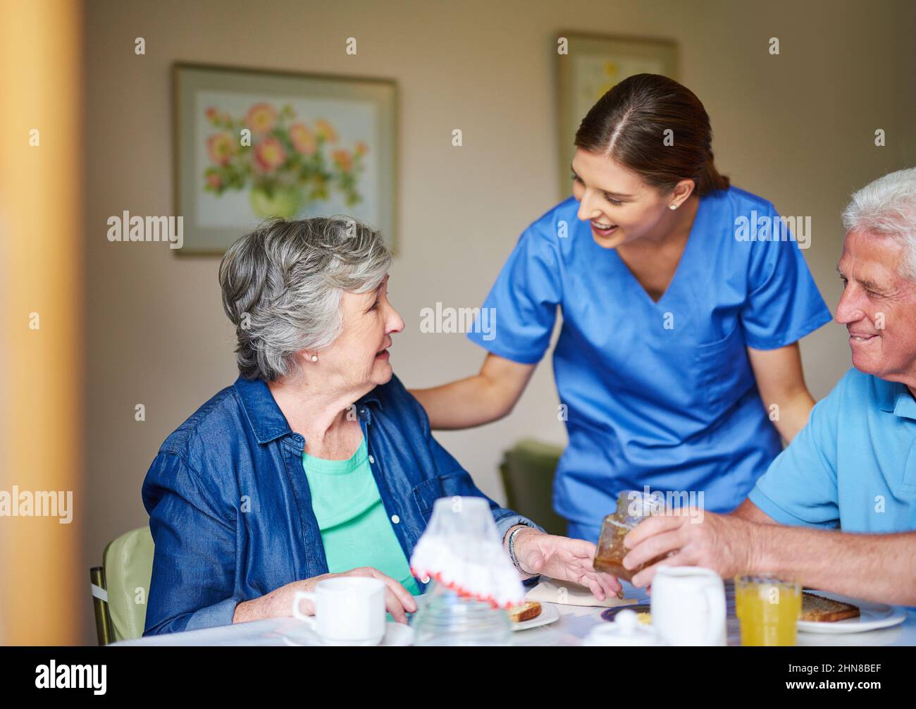 I trust breakfast was good this morning. Shot of two residents and a nurse at a retirement home. Stock Photo