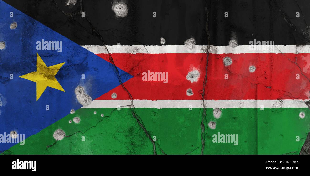 Full frame photo of a weathered flag of South Sudan painted on a cracked wall with bullet holes. Crisis and civil war in South Sudan concept. Stock Photo