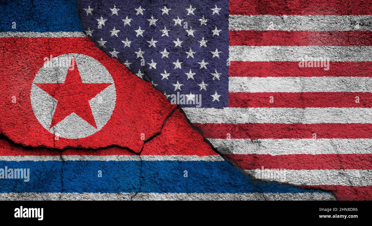 Full frame photo of a weathered flags of North Korea and the United States (USA, US, America) painted on a cracked wall. Stock Photo