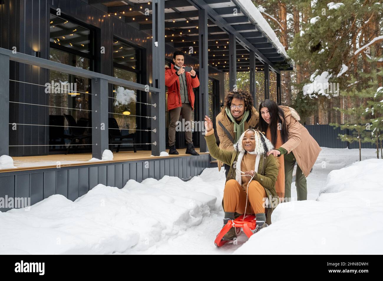 Group of friends having fun sledding on the sledge during winter vacations near their country